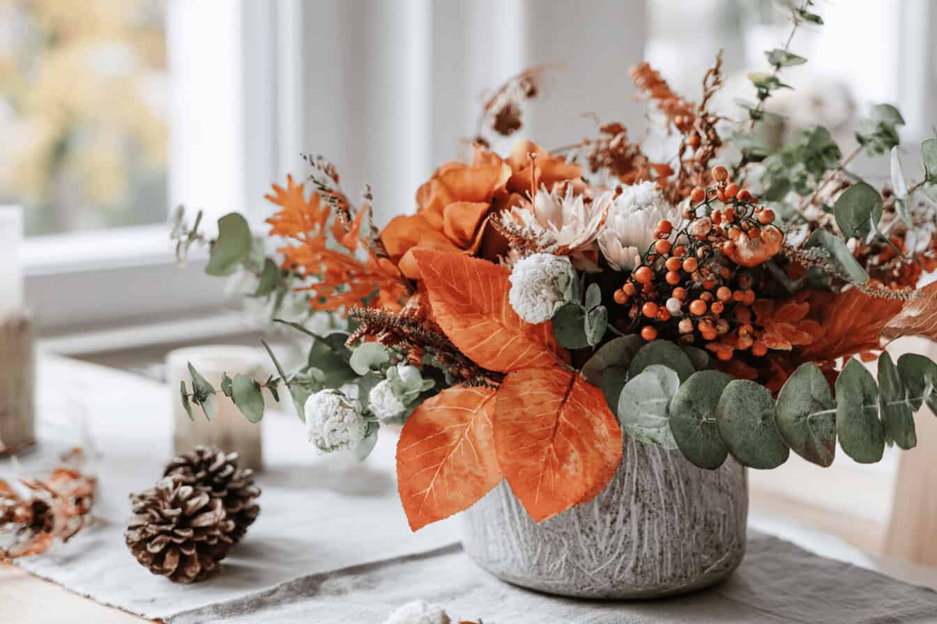 Herbstlicher Blumenstrauß mit Tannenzapfen auf Tisch